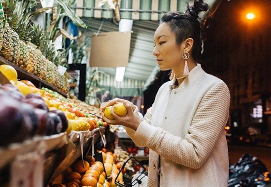 A woman choosing fruit at a market stall.