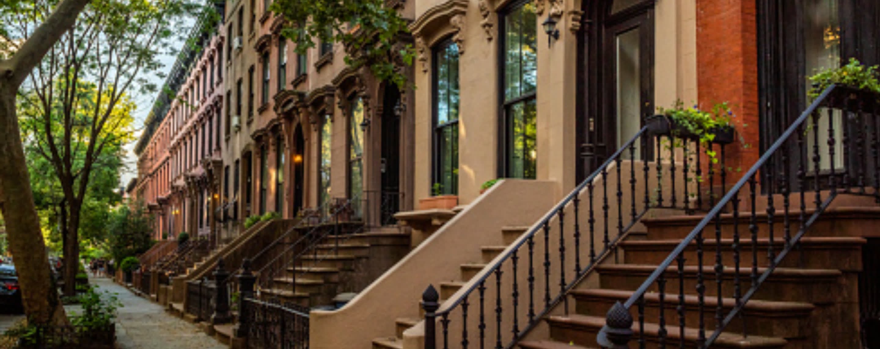 A row of Brooklyn brownstones along a tree-lined street.