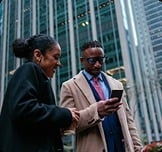 Two colleagues looking at a phone on a city street.
