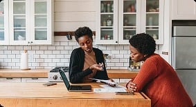Two people reviewing paperwork at a kitchen island.